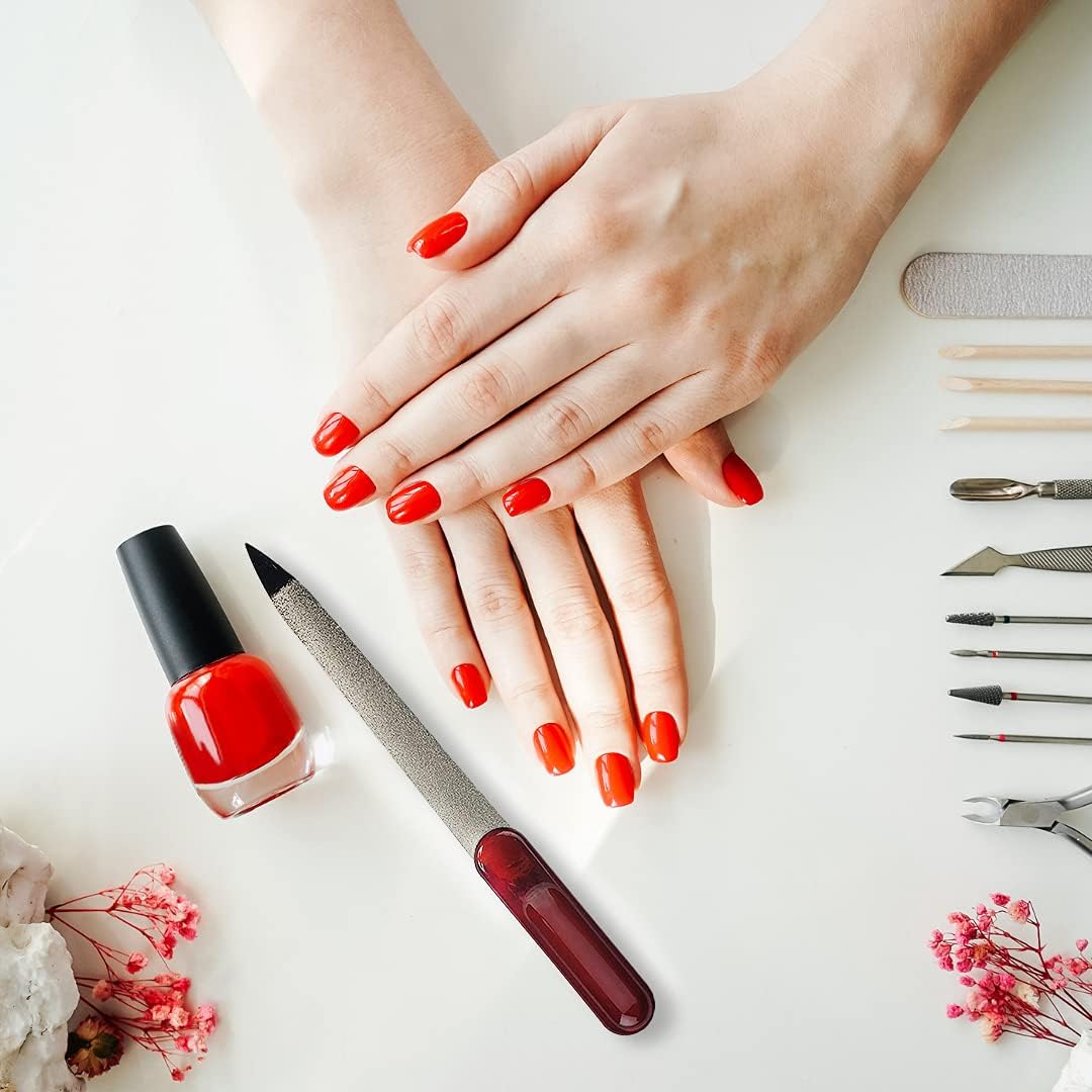 Flat lay of hands with red nail polish, La Cross Sapphire Nail File, and manicure tools on a white background
